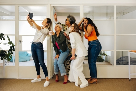 Happy businesspeople taking a group selfie in an office