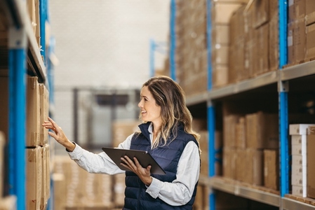 Cheerful woman checking shipping labels in a distribution warehouse