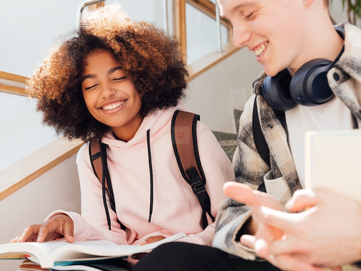 Classmates sitting together on a stairs preparing home assignments