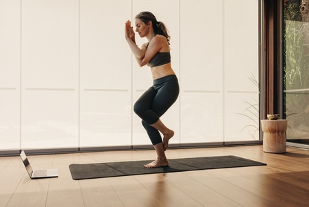 Senior woman doing a one legged asana during an online yoga class
