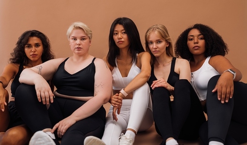Five diverse women in sportswear sitting together and looking at the camera