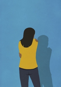 Woman hugging herself at blue wall