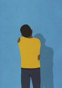 Man hugging himself at blue wall