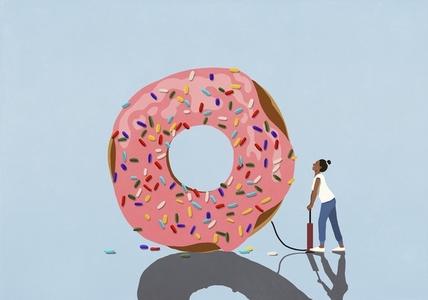 Woman with bicycle pump inflating large donut with sprinkles