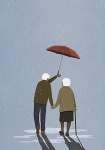 Affectionate senior husband holding umbrella over wife in rain