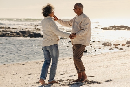 Happy elderly couple dancing together at the beach