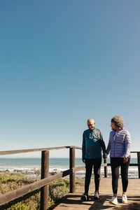 Retired senior couple taking a walk along a bridge at the beach