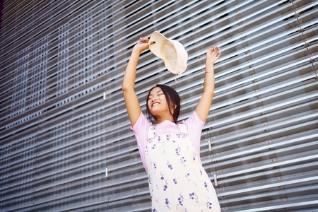 Young Asian woman dancing with raised arms