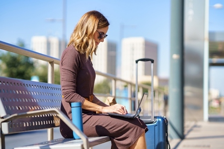 Businesswoman using laptop on bench