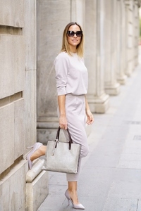 Stylish business woman with handbag standing near building