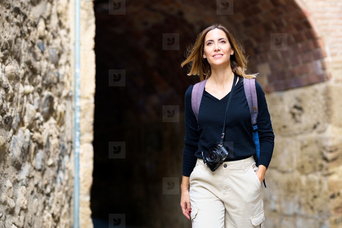 Positive woman smiling while sightseeing old city during holiday