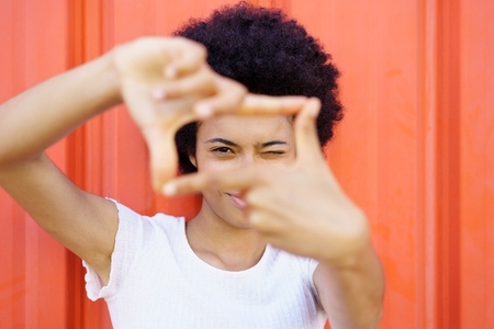 Content black woman making frame gesture near wall
