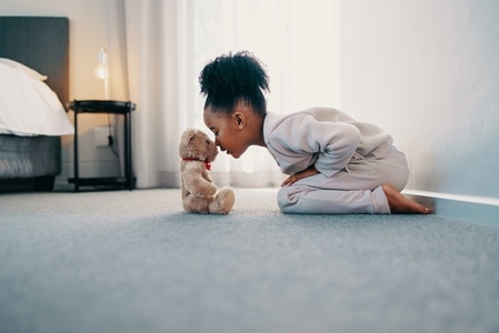 Girl touching noses with her teddy bear