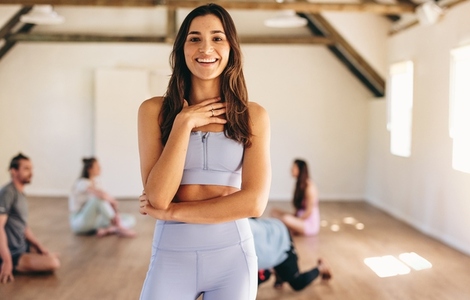Fit woman smiling at the camera in a yoga studio