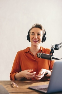 Happy female podcaster smiling in a home studio
