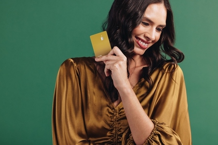 Enjoying a healthy credit score Female customer holds up her gold bank card in a studio