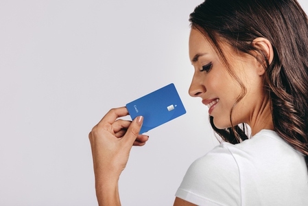 Smiling into the new era of banking Happy woman holds a bank card in a studio
