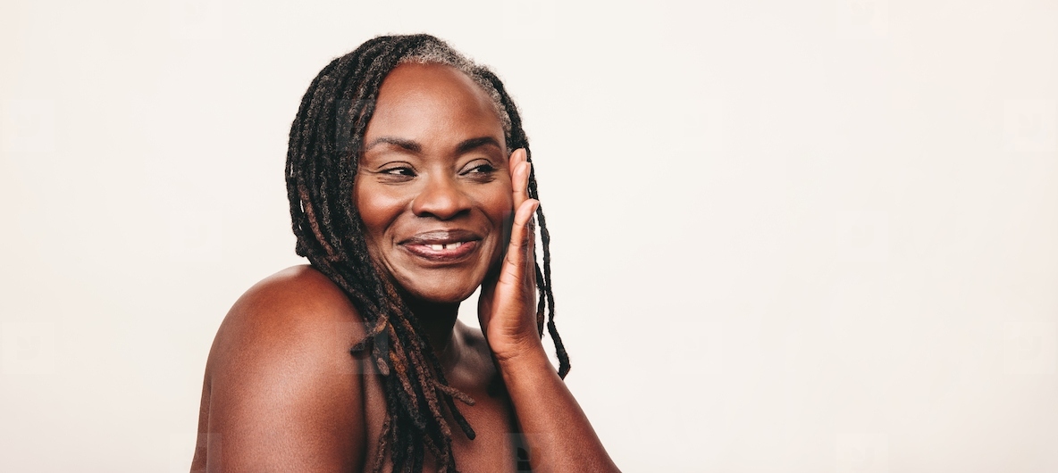 Happy mature woman with dreadlocks touching her flawless skin