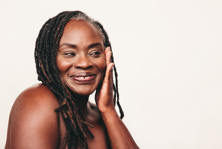 Happy mature woman with dreadlocks touching her flawless skin