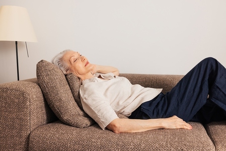 Aged woman sleeping on a couch  Senior female lying on a sofa in living room with closed eyes