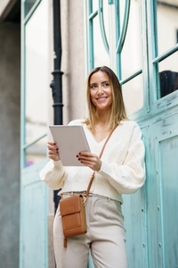 Positive female using tablet on town street