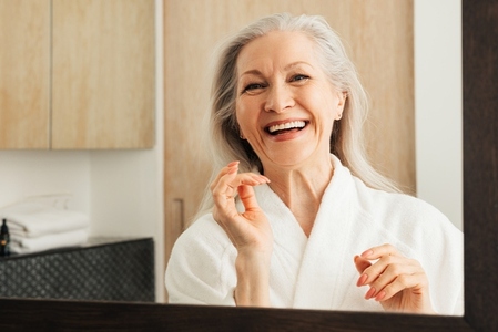 Happy mature woman with grey hair in the bathroom  Smiling female in a bathrobe