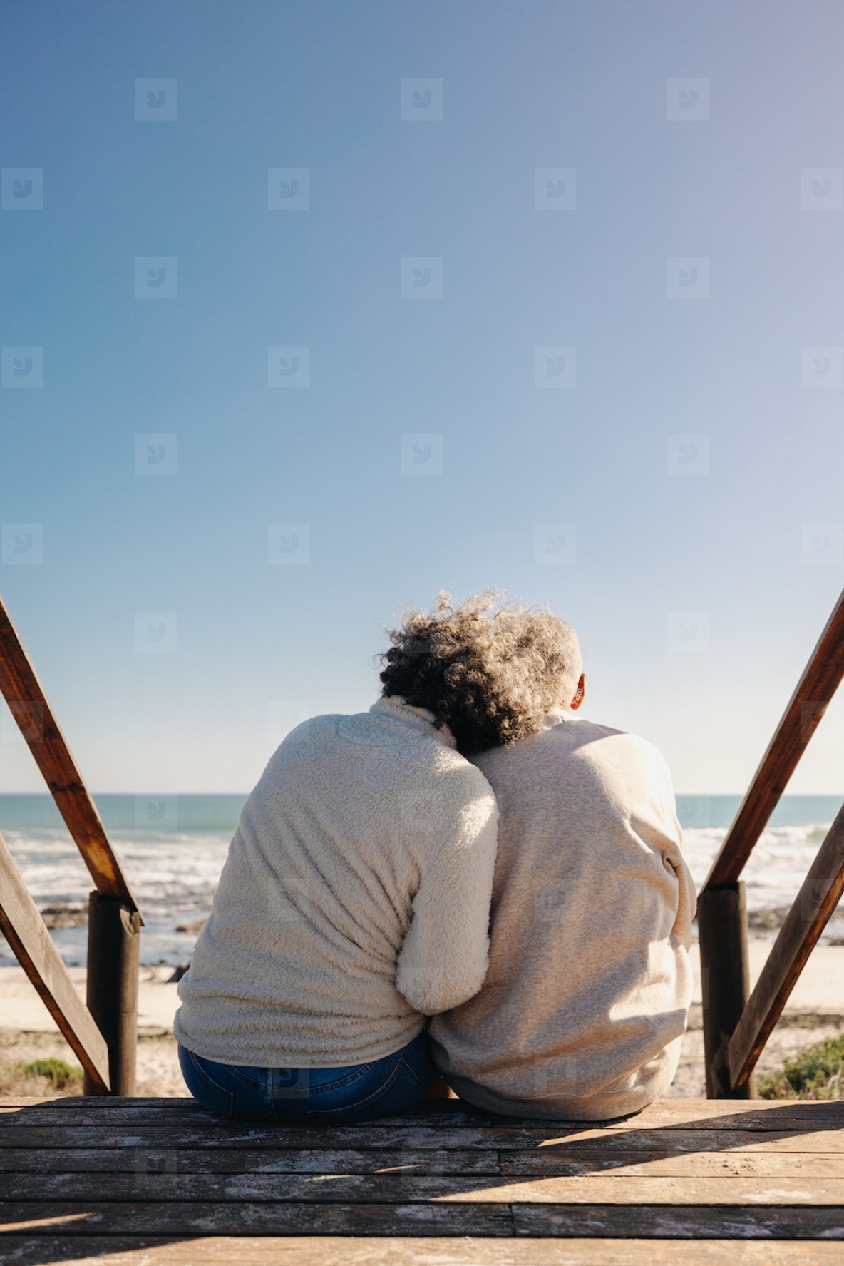 Elderly couple sitting on a foot bridge at the beach