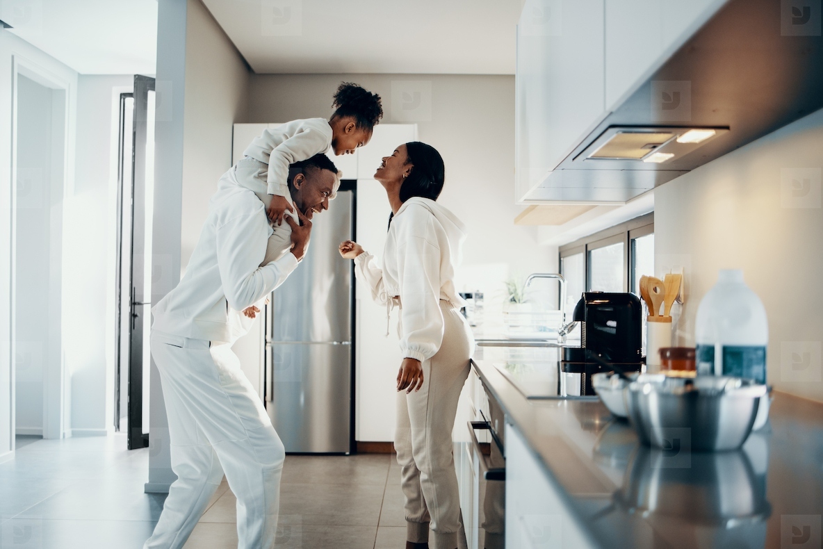 Happy family moments at home, mom and dad are playing with their daughter in the kitchen
