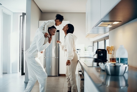 Happy family moments at home  mom and dad are playing with their daughter in the kitchen