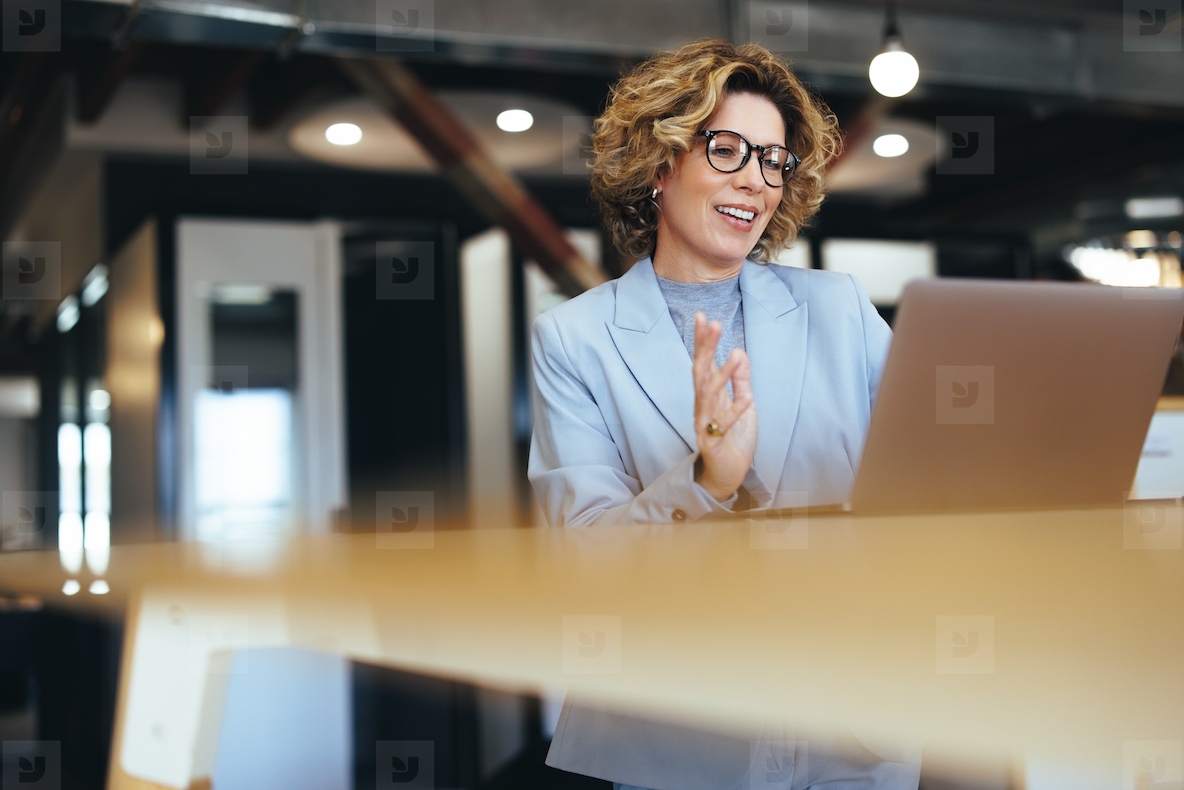 Business woman waving on a video call in a coworking office