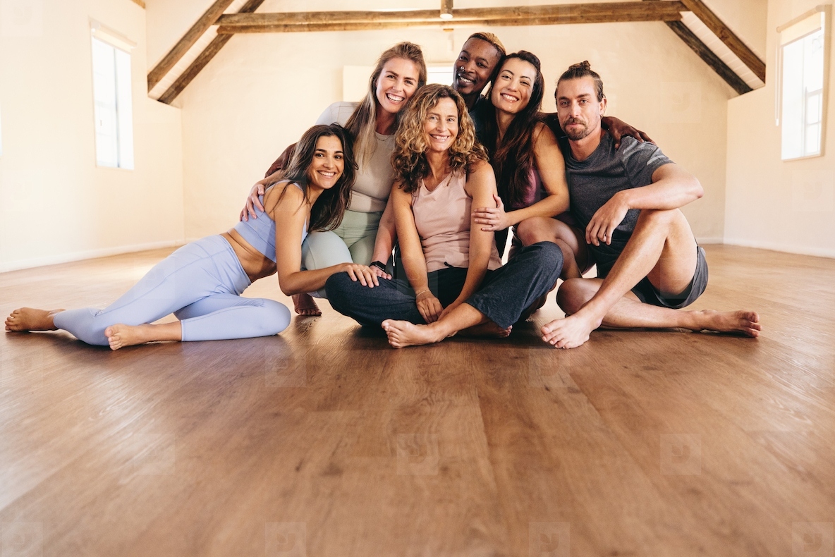Portrait of happy people sitting on the floor in a yoga studio