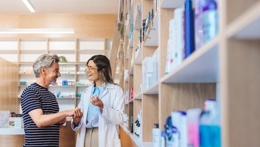Friendly pharmacist assisting a man in a chemist