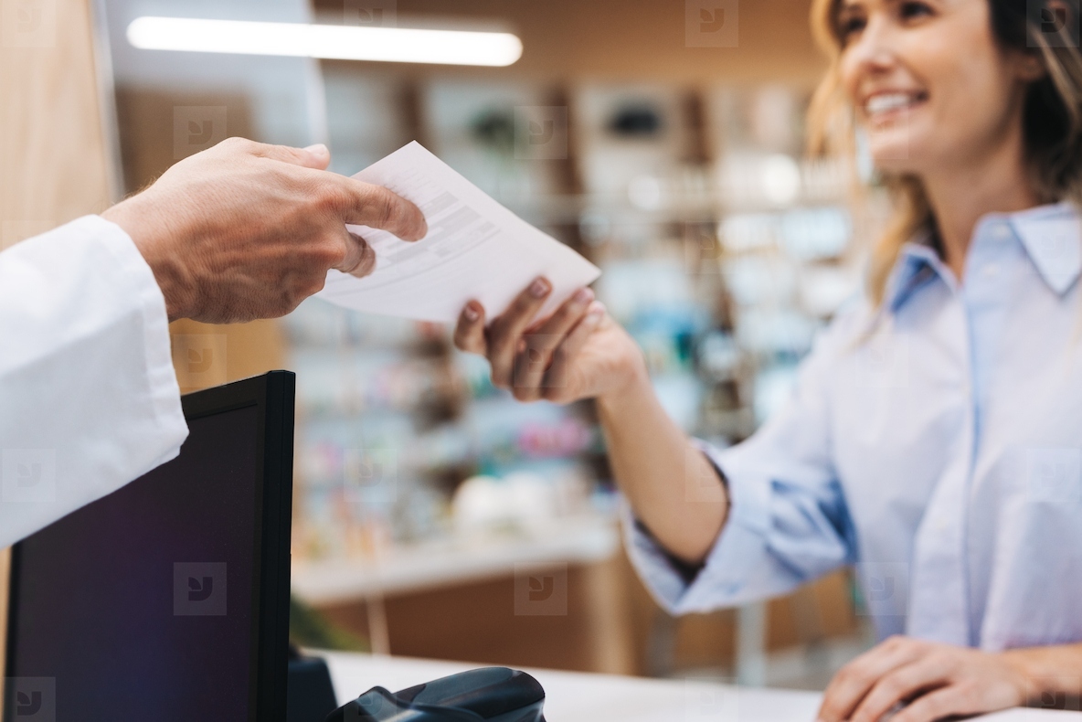 Patient handing a pharmacist a doctors prescription