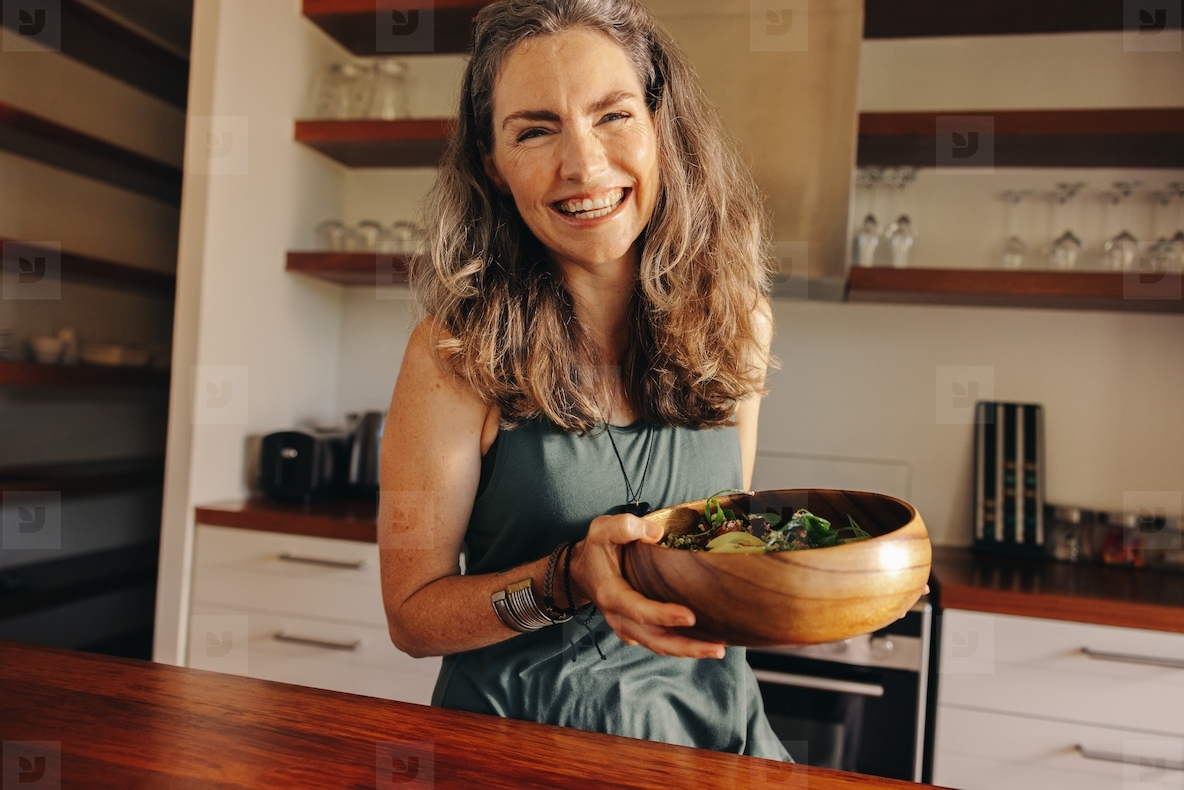 Healthy senior woman smiling happily while holding a buddha bowl