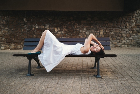 Woman in a dress relaxing on a bench