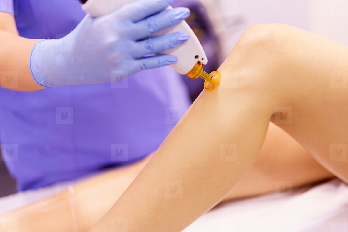 Woman receiving legs laser hair removal at a beauty center
