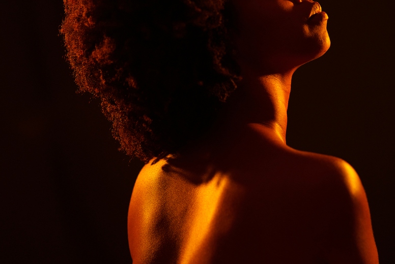 Calm black woman embracing naked torso