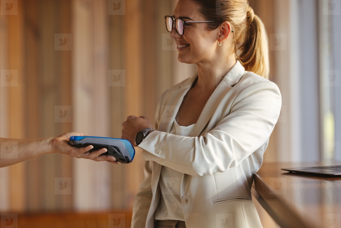 Paying for coffee with contactless payment smartwatch at cafe   happy female worker