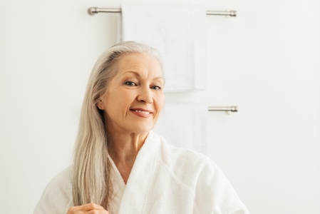 Smiling senior woman with long gray hair looking at her reflection