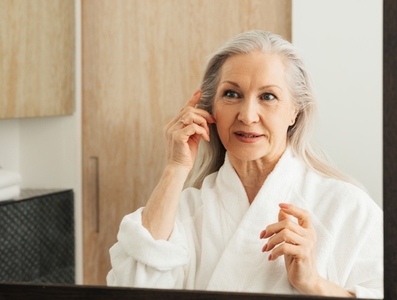 Aged woman with grey hair looking at her reflection