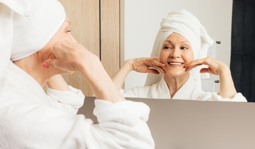 Senior female with a towel wrapped around her head enjoying her morning routine in the bathroom