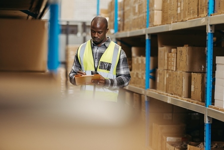 Black logistics manager taking inventory in a warehouse