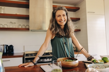 Happy vegan woman preparing a plant based meal at home
