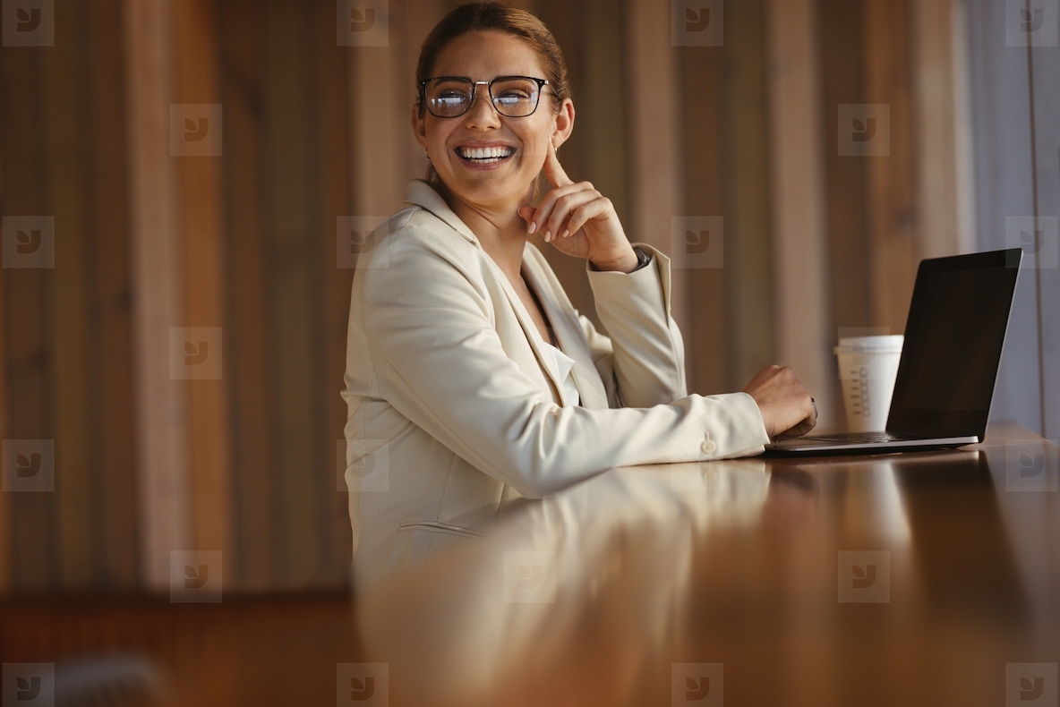 Happy business woman sitting in a coworking space with a laptop