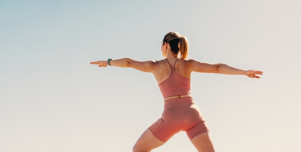 Woman practicing warrior pose outdoors in sportswear for physical fitness  wellbeing and health