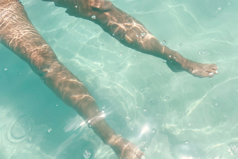 Legs of an unrecognizable woman in transparent ocean water