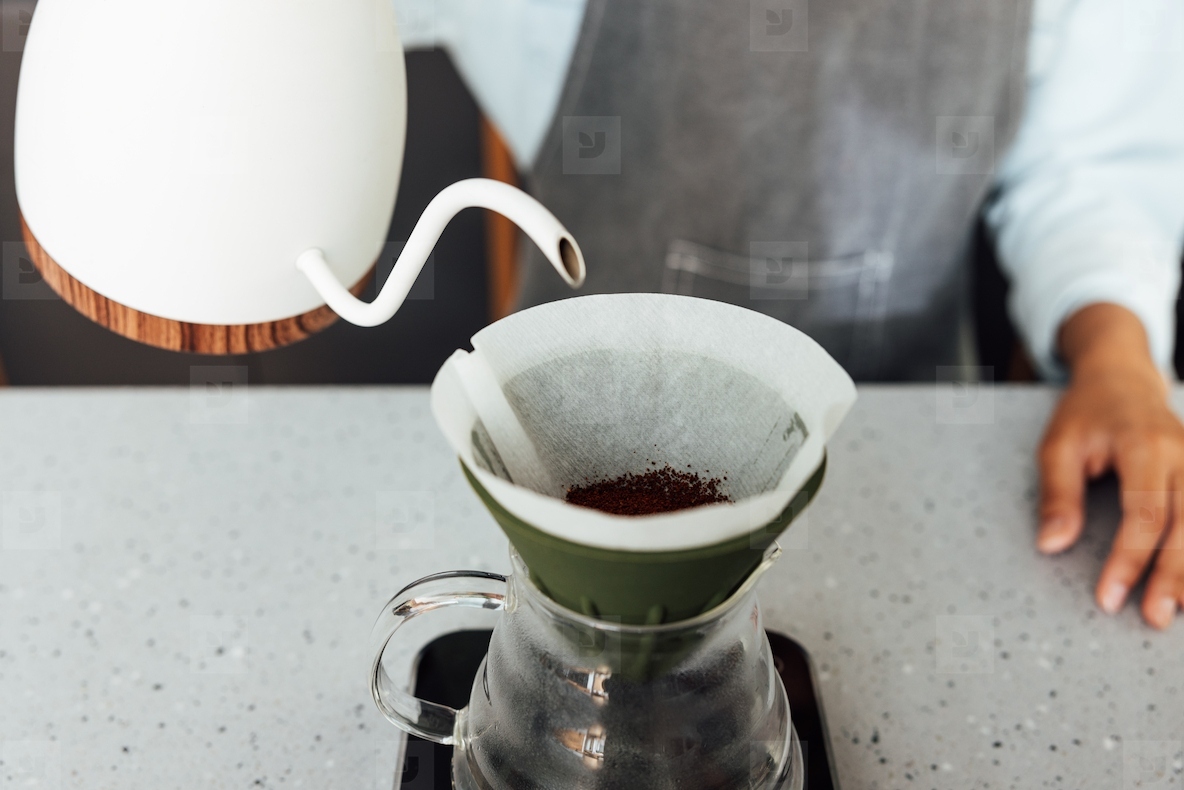 Close-up of an unrecognizable barista brewing coffee with a filter. Process of a gravity-based method of brewing coffee