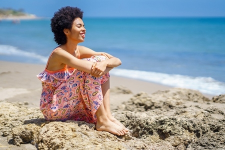 Happy African American woman spending time on beach