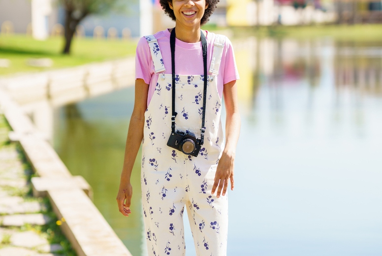 Content black woman with photo camera near lake
