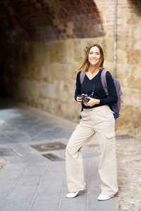 Cheerful lady with photo camera smiling on street during sightseeing trip